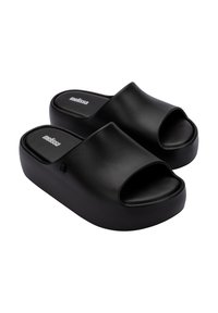 Sandales à plateforme noires avec un design à bout ouvert, en matériau synthétique lisse et au style minimaliste. Présente un logo sur la semelle intérieure.