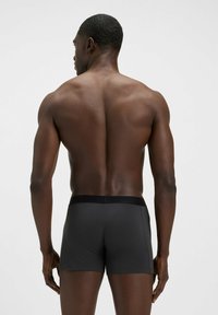 Boxer di cotone nero dalla texture liscia, con un design semplice e una cintura elastica nera, visti dal retro.