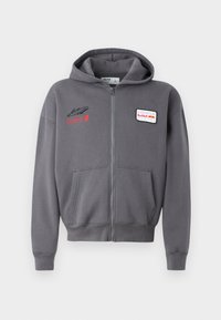 Gray zip-up hoodie with a drawstring hood, front pockets, and embroidered logos in red and white. Soft fabric with a relaxed fit.