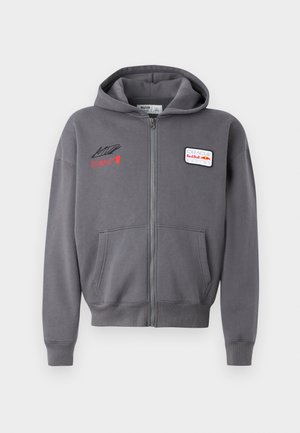 Graue Zip-Hoodie mit verstellbarem Kapuzenzug, Fronttaschen und gestickten Logos in Rot und Weiß. Weicher Stoff mit lässigem Schnitt.