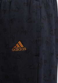 Marineblauer Stoff mit dezenten schwarzen sportlichen Grafiken und orangefarbenem, gesticktem Adidas-Logo.
