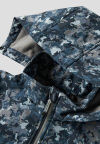 Veste à motif camouflage dans des tons de bleu et de gris. Dispose d'une capuche doublée, d'un devant zippé et d'un tissu lisse et texturé.