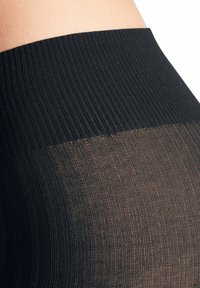 Collant neri opachi con una fascia in vita a coste larghe e una sezione trasparente con righe orizzontali, che mette in evidenza i contrasti di texture nei tessuti.