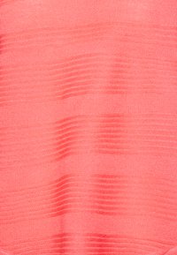 Tissu en tricot corail clair présentant un motif texturé avec des rayures horizontales, créant un effet visuel subtil. Texture lisse et douce.