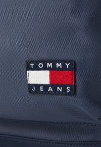 Tommy Jeans logófeltét sötétkék textúrázott anyagra hímzett tengerészkék, fehér és piros színekben.