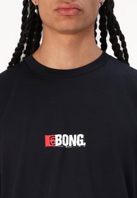 Black cotton t-shirt features a round neck and short sleeves, with a red and white graphic logo print on the chest.