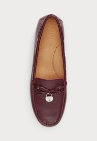 Burgundinnehållen lädermoccasin med rund tå, dekorativ snörning och silverfärgad logo charm. Interiören har perforerad dämpning.