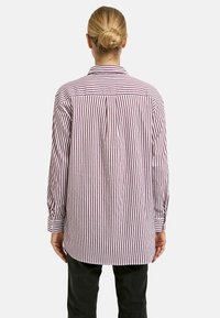 Long-sleeve shirt with red and white vertical stripes, buttoned cuffs, and a relaxed fit. Collar and back pleat visible.
