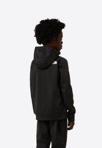 Fekete kapucnis pulóver puha, texturált anyagból, kenguruzsebbel és állítható húzózsinóros kapucnival. Az elején a felső háton egy kis logó található.