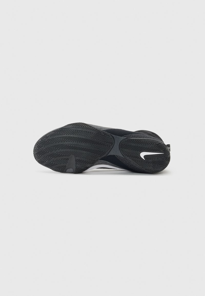 Schwarzer Sportschuh mit einer strukturierten Gummisohle und einem weißen Logo. Das Obermaterial zeichnet sich durch ein elegantes Design aus, das aus Mesh- und synthetischen Materialien besteht.