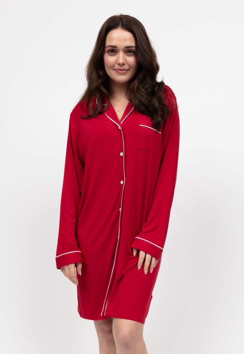 Robe da pigiama rossa con maniche lunghe, chiusura frontale con bottoni, piping bianco e taschino sul petto. Realizzata in un tessuto morbido e liscio.