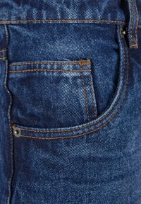 Tummansiniset farkut, joissa on takatasku ompeluyksityiskohdalla ja hopeinen napitussukko. Sileä pinta, jossa on lievää kulumista.