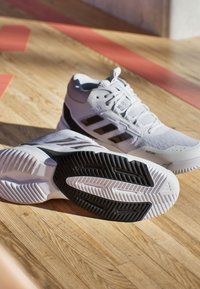 Białe buty sportowe z czarnymi akcentami, z teksturowaną podeszwą, sznurówkami oraz syntetycznym materiałem dla wytrzymałości i wsparcia.