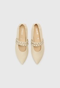 Beežid teravnurgelised tantsijalatsid elastsete avade ja kahekordsete rihmadega, millel on hõbedased naelad. Sile materjal mattviimistlusega.