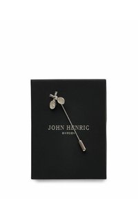 Silver tennisracket brosch på en svart låda med silverfärgad text "John Henric Sweden" centrerad på lådan.