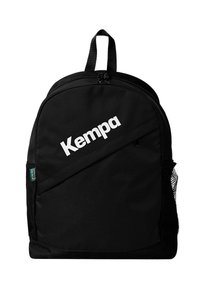 Mochila negra con un acabado de tela suave, que presenta un gran logo blanco de "Kempa", un asa superior y un bolsillo de malla lateral.