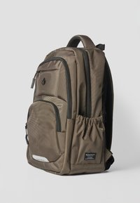 Sac à dos marron à multiples poches avec fermetures éclair noires, poche latérale élastique pour bouteille d'eau, poignée supérieure et étiquettes de marque visibles à l'avant.