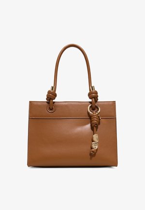 Bruine leren handtas met geknoopte handvatten en goudkleurige decoratieve bedels die aan één handvat hangen.