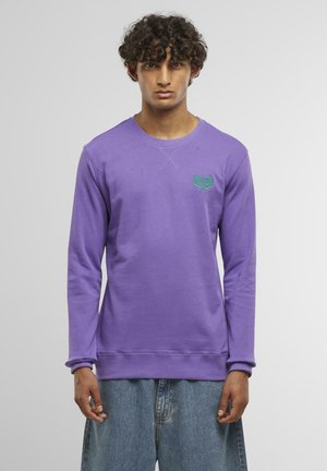 Lila Sweatshirt mit langen Ärmeln, Rundhalsausschnitt und grünem, gesticktem Logo auf der Brust. Hergestellt aus weichem Stoff mit einer glatten Textur.