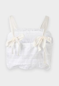 White cropped top featuring layered lace and sheer fabric, with wide straps and ribbon ties on the front for adjustable fit.