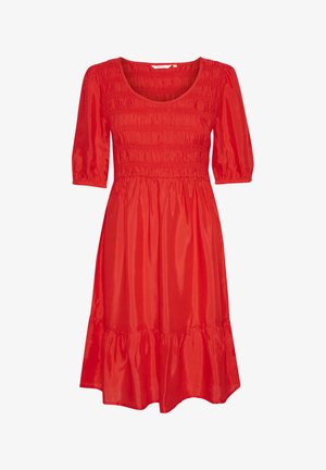 Punane lühikeste varrukatega kleit, millel on smockitud bodi ja kihiline, laienev äär. Valmistatud siledast kangast, millel on läikiv viimistlus.