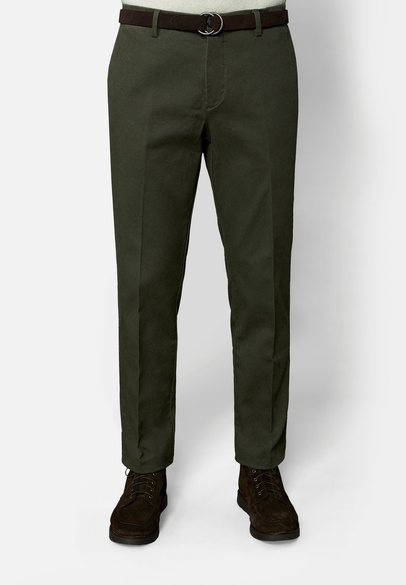 Pantalon droit vert foncé associé à une ceinture marron foncé et des bottines marron foncé à lacets, montré de la taille aux pieds.