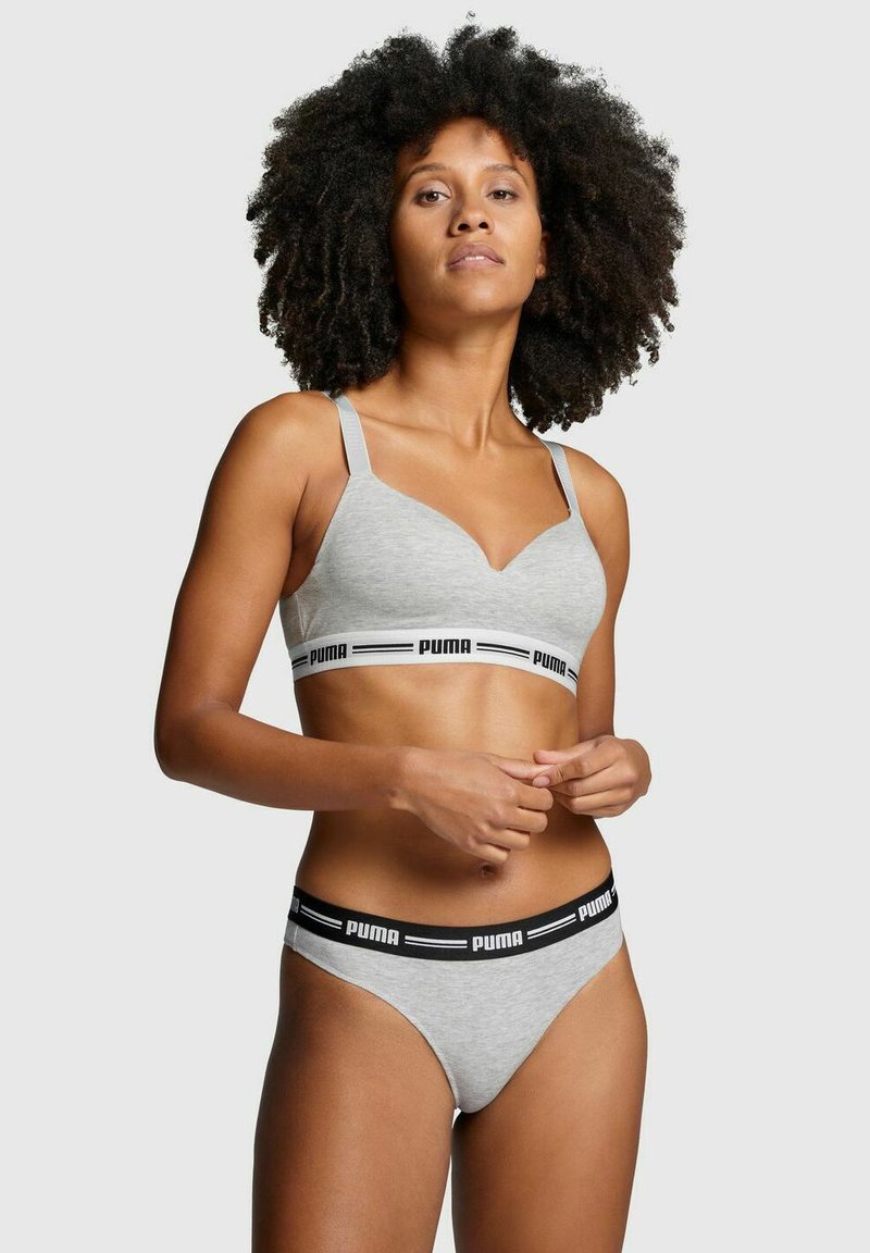 Grauer Sport-BH mit verstellbaren Trägern und schwarzem Logo-Band; kombiniert mit passendem grauen Tanga. Beide Artikel verfügen über eine glatte Textur und ein minimalistisches Design.