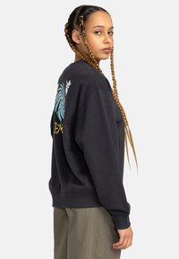 Black sweatshirt with a loose fit, featuring colorful graphic designs on the back, ribbed cuffs, and a round neckline.