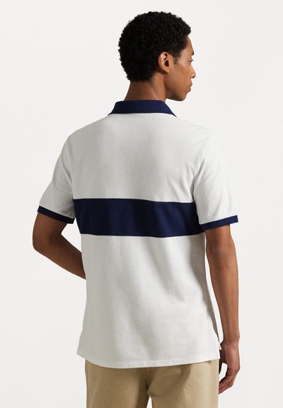 Witte polo met een marineblauwe horizontale streep, korte mouwen en een marineblauwe kraag. Gemaakt van een zachte katoenmix met een gladde textuur.