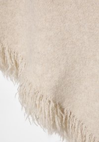 Beige villahuivi, jossa on pehmeä rakenne ja hienovarainen kuvio, esittelee lämpimän, neutraalin sävyn ja käsinkudotun viimeistelyn reunoissa.