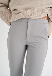 Šedé kalhoty na míru z hladkého, lehkého materiálu, s plochým předním dílem, bočními kapsami a moderním, úzkým střihem.