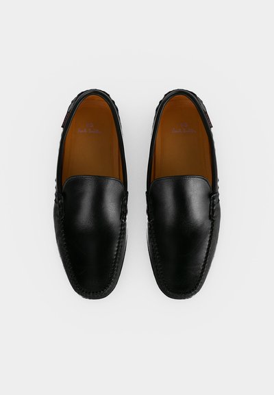 Paire de mocassins noirs en cuir sans lacets avec des détails cousus et des semelles intérieures marron, vue de dessus sur fond blanc.