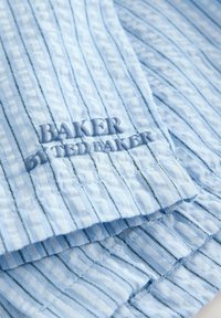 Tissu texturé bleu clair avec de fines rayures verticales sombres et texte brodé "BAKER BY TED BAKER" en fil bleu assorti.