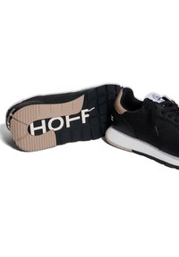Sneaker nera con tomaia liscia e dettagli in beige chiaro. Presenta una suola in gomma testurizzata con il marchio "HOFF" in bianco sulla parte inferiore.