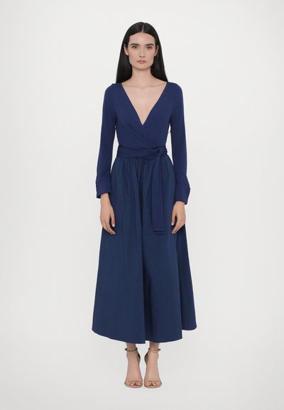 Tmavě modré zavinovací šaty s dlouhými rukávy, hlubokým výstřihem do V a zavazováním v pase. Rozšířená sukně sahá do poloviny lýtek. Hladká látka s jemnou strukturou.