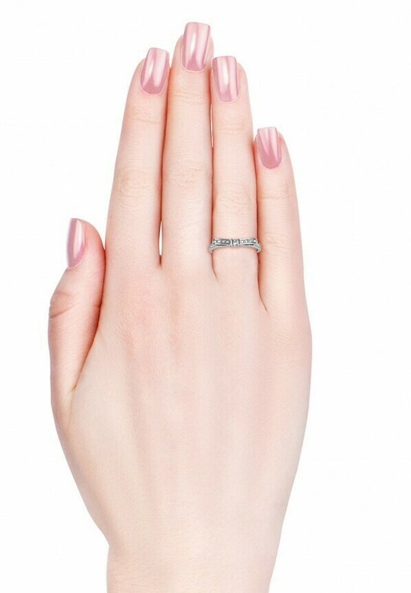 Anello d'argento con un design della fascia caratterizzato da piccoli gemstone trasparenti, indossato su una mano con pelle chiara e lunghe unghie nude lucidate.