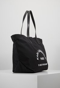 Sac fourre-tout en nylon noir avec texte décoratif blanc "Karl Lagerfeld Paris 21 Rue St-Guillaume", doté de deux longues poignées en cuir noir.