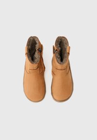 Tan enkellaarsjes van suede met een zachte, nep bont voering. Ze hebben zijritsen en een platte rubberen zool voor comfort.