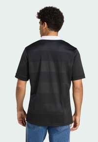 Zwarte shirt met korte mouwen, voorzien van een witte kraag en een gestructureerd gestreept patroon. De stof lijkt lichtgewicht en ademend te zijn.
