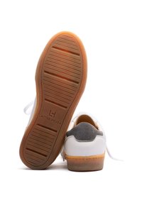 Lactae Hevea Schuhe mit einem weißen Leder-Obermaterial, grauem Wildlederabsatz und Gummisohle; Merkmale sind das strukturierte Profil und ein Logo auf der Sohle.