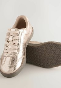 Metallisch roségoldene Sneakers mit strukturiertem Finish, Schnürdesign und Gummisohle mit einem gemusterten Profil für besseren Halt.