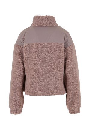 Vue arrière d'une veste en polaire sherpa mauve avec un col haut et un panneau en tissu lisse sur le haut du dos et les épaules.