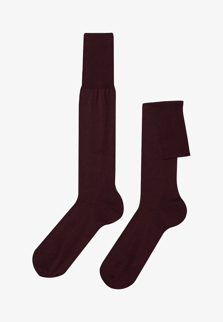 Par de calcetines altos hasta la rodilla de color marrón oscuro, uno completamente extendido y otro doblado en la parte superior, mostrados sobre un fondo blanco.