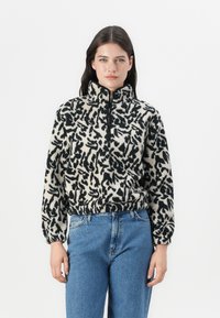 Pullover in pile bianco e nero con colletto alto e zip a quarter, caratterizzato da un motivo astratto, vestibilità rilassata e orlo elastico.