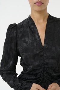 Black dress made of silky fabric with a subtle textured pattern, featuring a deep V-neck and gathered detailing at the waist and cuffs.