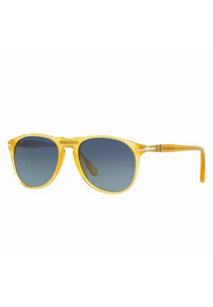Occhiali da sole in acetato giallo con lenti blu sfumate, montatura leggera e dettagli testurizzati sulle aste. Forma arrotondata con un design classico.