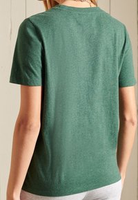 Camiseta de manga corta verde hecha de tela ligera, con un clásico cuello redondo y una textura suave y sutil.