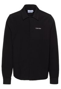 Sort langærmet skjorte lavet af glat stof. Har en button-down krave, let tekstur og Calvin Klein-logo i hvidt på brystet.