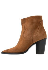 Brun ruskind ankelstøvle med spids tå, skulptureret sidedetalje og 7 cm sort blokhæl. Glat tekstur med et sømfrit design.