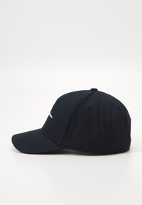 Sötétkék baseballsapka, amely szövetből készült, ívelt karimával és hímzett szöveggel az elején. Szellőző lyukakkal rendelkezik és zárt hátoldala van.